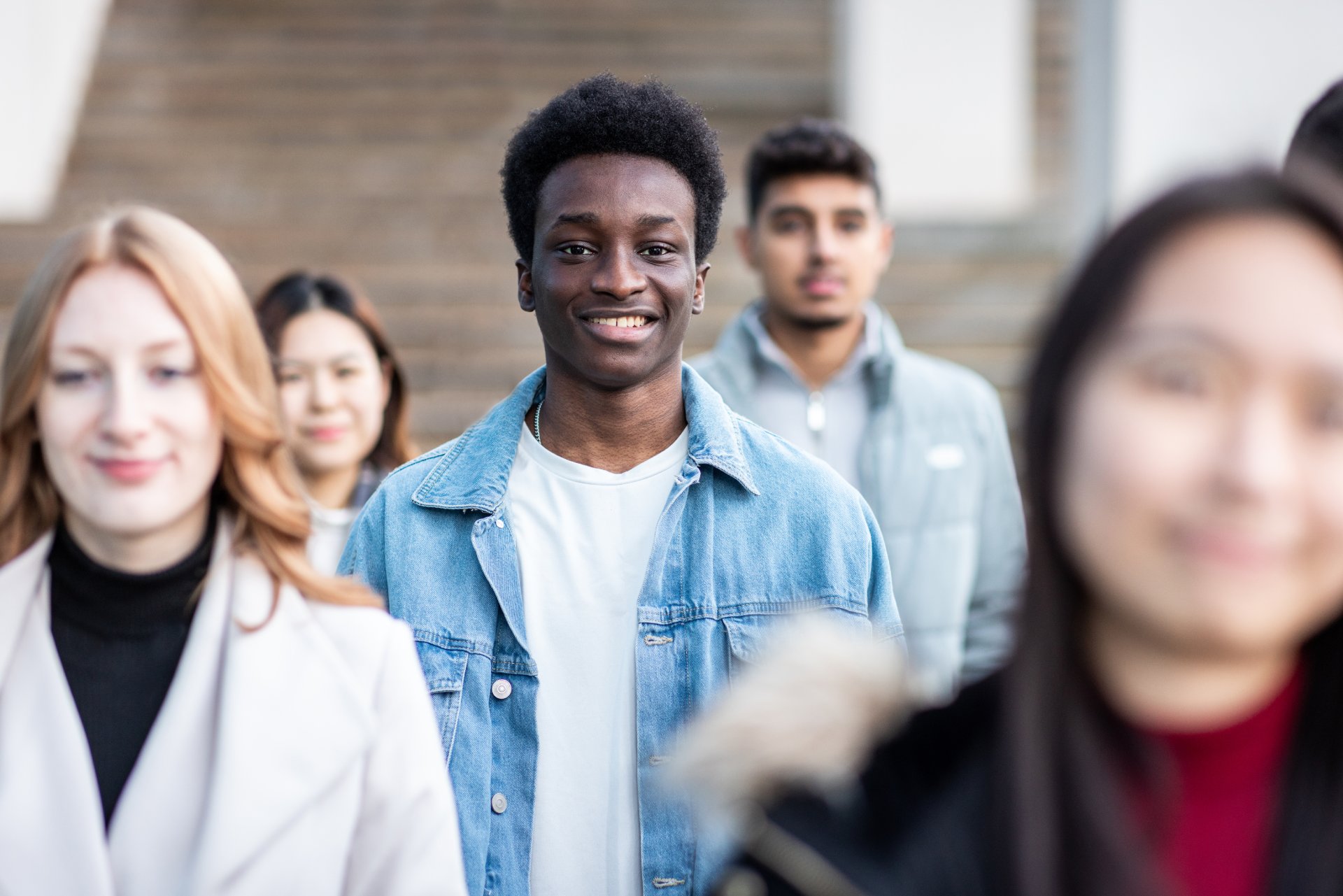 Multiracial crowd of people in the city commuting and walking on pavement Authentic shot multiracial crowd of people in the city walking on the pavement commuting to work - Lifestyle and city life concepts with young people - Focus on smiling black man