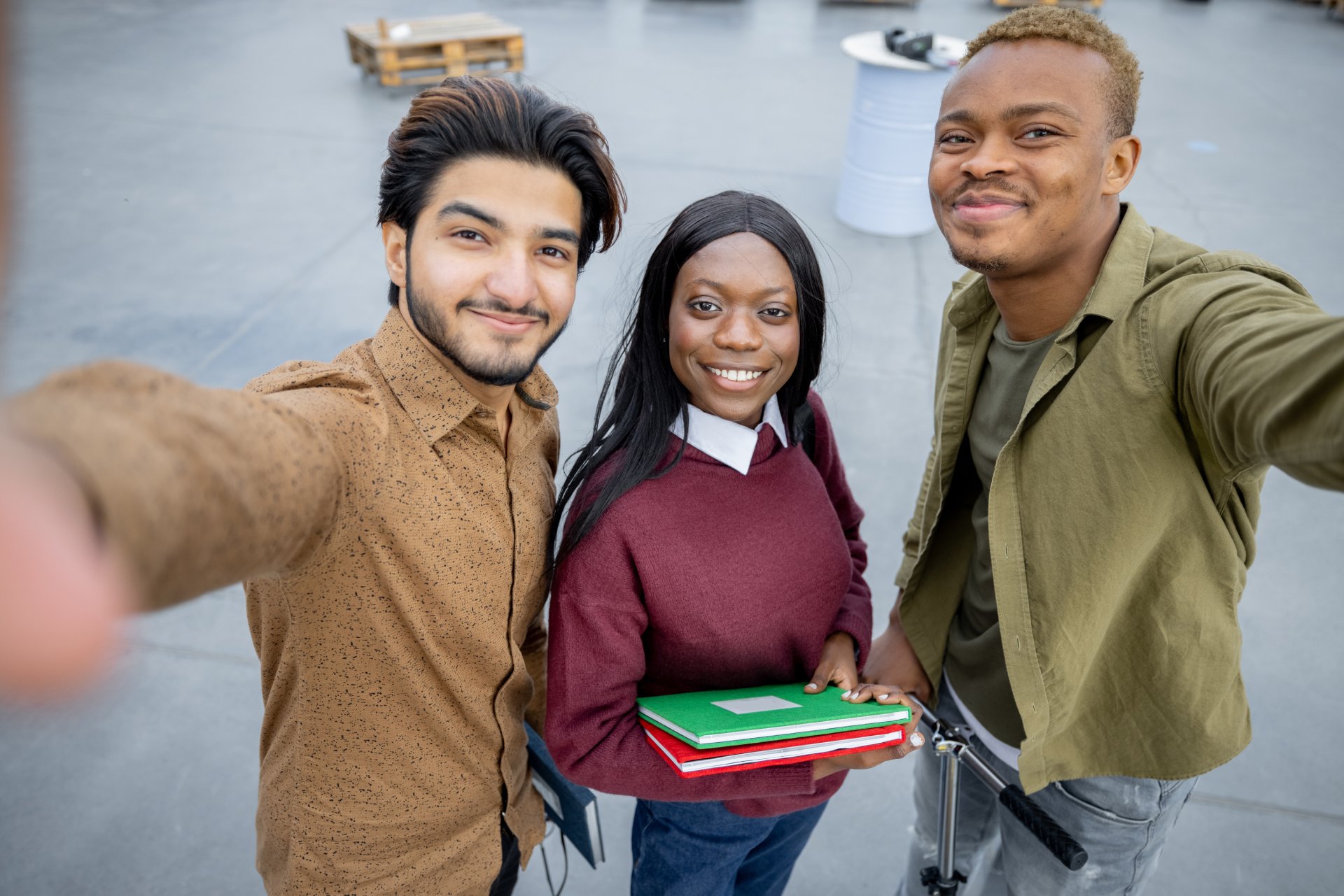 Students looking at camera at university campus Group of multiracial students looking at camera on territory of university campus. Concept of education and learning. Idea of student lifestyle. Friendship. Black man with electric scooter